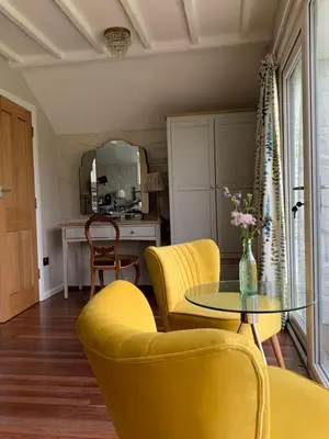 a living room with yellow chairs and a glass table at Ty Capel in Llanidloes