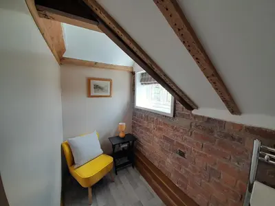 a room with a yellow chair and a brick wall at The Dolfor Inn in Newtown