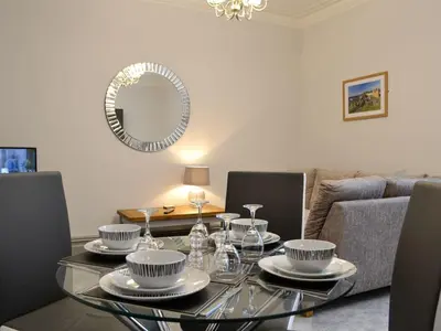 a dining room with a glass table and a mirror at Grosvenor House APT 3 in Aberystwyth
