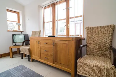 a living room with a wooden dresser and a tv at Cambrian View in Aberystwyth