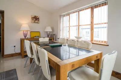 a dining room with a long table and white chairs at Cambrian View in Aberystwyth