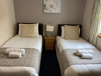two twin beds in a room with a night stand at Cambrian View in Aberystwyth