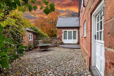 a building with a bench next to a house at Pear Tree Cottage Courtyard in Shrewsbury