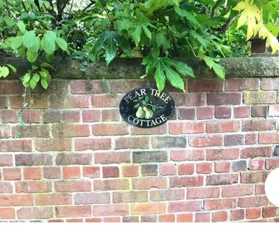 a brick wall with a sign that reads take the coffee at Pear Tree Cottage Courtyard in Shrewsbury