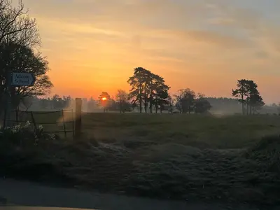 a sunset in a field with a fence and trees at Pear Tree Cottage Courtyard in Shrewsbury