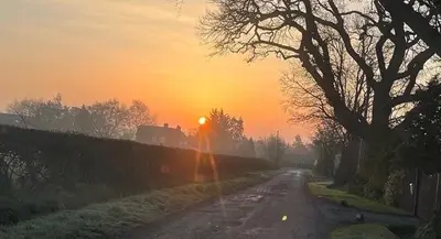 a person walking down a dirt road at sunset at Pear Tree Cottage Courtyard in Shrewsbury