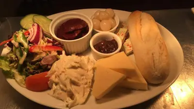 a plate of food with a sandwich and salad and cheese at Crown Inn in Rhayader
