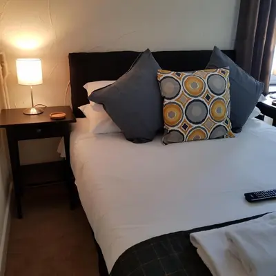 a bed with pillows and a lamp on a table at Crown Inn in Rhayader
