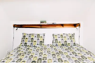 a bed with a wooden headboard and two pillows at The Stable at Ty Beic in Bala