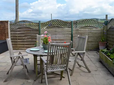 a table with two chairs and a table with flowers on a patio at Morolwg in Borth