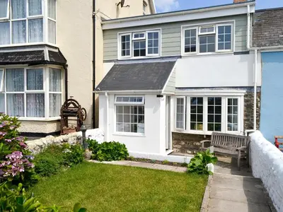 a white house with a bench in the yard at Morolwg in Borth