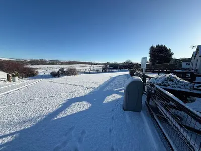 a snowy street with a fence and footprints in the snow at The Hay Suite in Aberystwyth