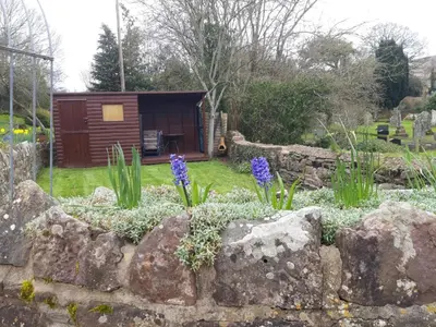 a garden with purple flowers and a log cabin at Penybont Barn in Llangorse