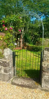a gate to a garden with pink flowers at Penybont Barn in Llangorse