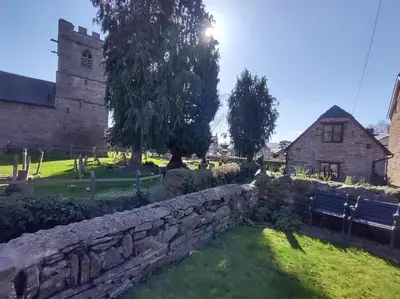 a stone wall next to a building with a church at Penybont Barn in Llangorse