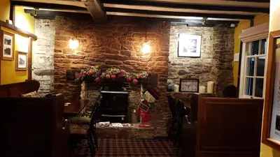 a restaurant with a stone wall with a fireplace at The Wheatsheaf Inn in Ludlow
