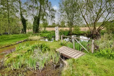 a small wooden bridge over a small pond at The Folly in Hereford