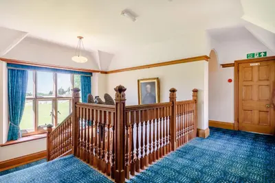 a room with a wooden staircase and a door at Plas Gwynfryn in Llanbedr