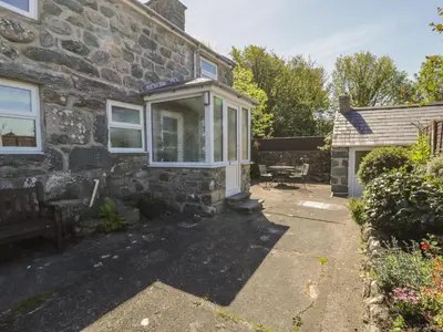 a stone house with a bench in front of it at Ty Uchaf in Dyffryn