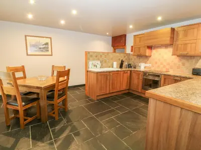 a kitchen with wooden cabinets and a table and chairs at Craig Y Deryn in Tywyn