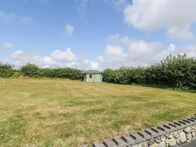 a small green building in a field with a grass yard at Craig Y Deryn in Tywyn