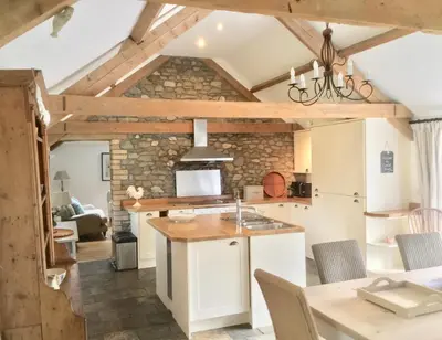 a kitchen with white cabinets and a table with chairs at Cuckoo Barn at Penygaer farm near the Brecon Beacons in Llandovery