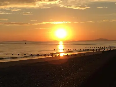 a sunset on the beach with birds in the water at Oceandrive in Barmouth