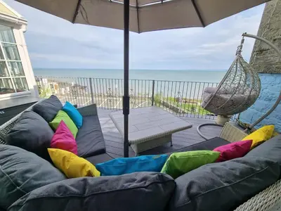 a couch sitting on a porch with an umbrella at The Sup Shack Wellington Inn in New Quay