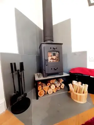 a stove with a bunch of logs in a room at Little Smithy in Shrewsbury