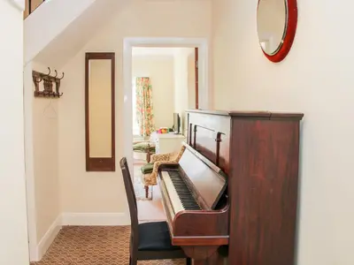 a piano in a living room with a mirror at Lane House in Bishops Castle