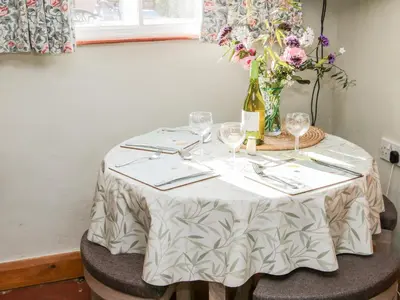a table with glasses and a vase of flowers on it at Ensdon Lea Cottage in Shrewsbury