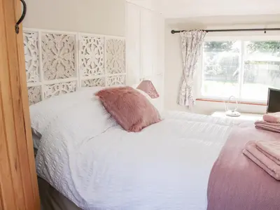 a bedroom with a bed with a pink pillow on it at Ensdon Lea Cottage in Shrewsbury