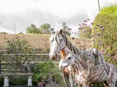 a statue of two horses in a field of flowers at Ensdon Lea Cottage in Shrewsbury