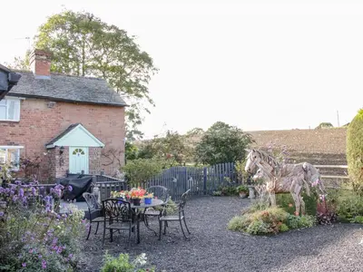 a garden with a table and a statue of a horse at Ensdon Lea Cottage in Shrewsbury