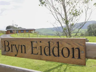 a wooden sign that reads bryn eldoria on a fence at Bryn Eiddon Log Cabin in Machynlleth