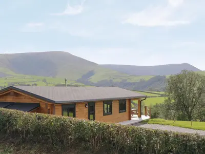 a wooden house with mountains in the background at Bryn Eiddon Log Cabin in Machynlleth