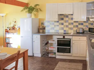 a kitchen with white cabinets and a white refrigerator at Cranberry Cottage in Shrewsbury