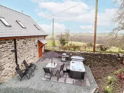 a patio with a table and chairs and an umbrella at Stabl, Plas Moelfre Hall Barns in Oswestry
