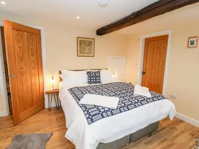 a bedroom with a large bed and a wooden floor at Stabl, Plas Moelfre Hall Barns in Oswestry