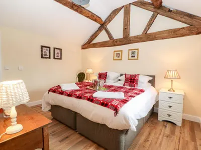 a bedroom with a large bed and a wooden floor at Cut Moch, Plas Moelfre Hall Barns in Oswestry