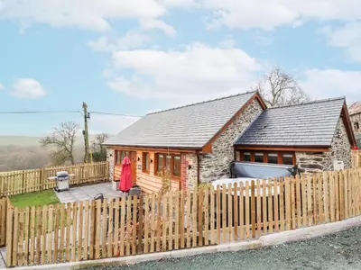 a wooden fence in front of a house at Cut Moch, Plas Moelfre Hall Barns in Oswestry