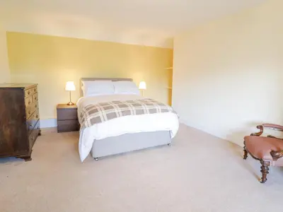 a bedroom with a bed and a dresser and lamp at Squires Rest in Welshpool