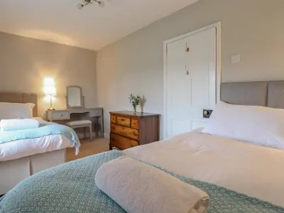a bedroom with two beds and a desk with a mirror at Squires Rest in Welshpool