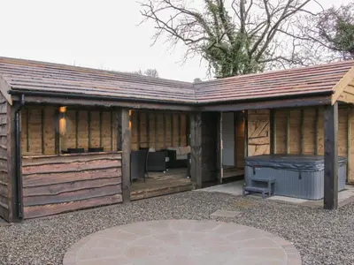a large wooden building with a hot tub at Hillside Lodge in Ludlow