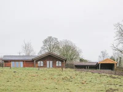 a log house in a field next to a field at Hillside Lodge in Ludlow