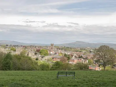 a bench sitting in a field overlooking a city at Hillside Lodge in Ludlow