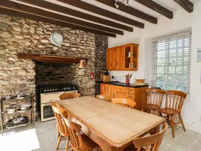 a kitchen with a wooden table and a stone wall at Dewi Villa in Aberaeron