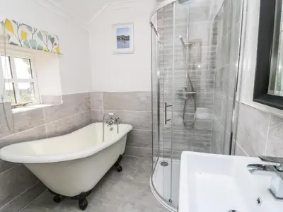 a bathroom with a tub and a shower and a sink at Dewi Villa in Aberaeron