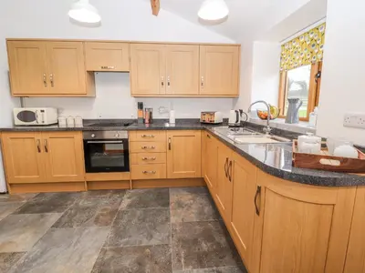 a kitchen with wooden cabinets and a counter top at The Old Cart House in Oswestry