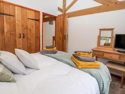 a bedroom with a large white bed and a tv at The Old Cart House in Oswestry